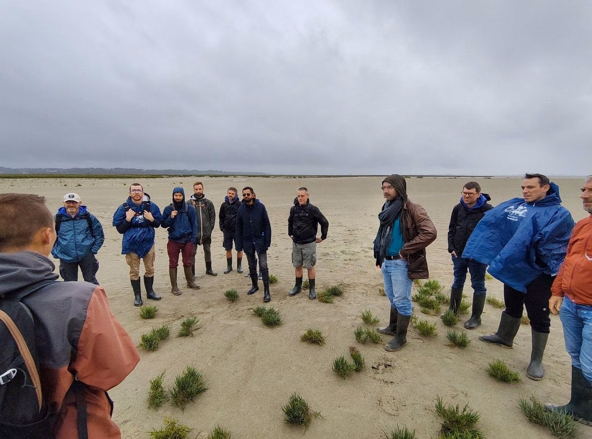 Le collectif en bottes, réuni en cercle sur le sable de la baie